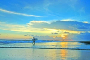 Canggu, Bali, featuring scenic rice fields, trendy beach clubs, and black sand beaches with surfers riding the waves.