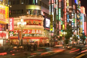 Night view of Shinjuku City with illuminated buildings and bustling street traffic.